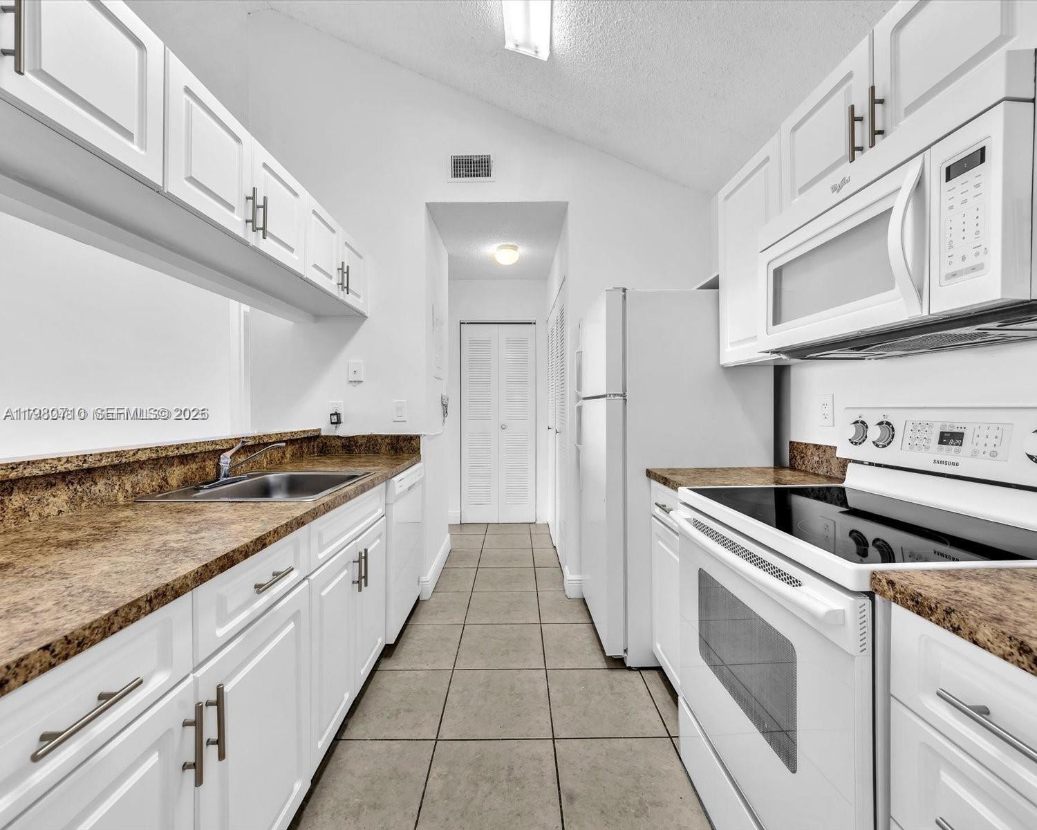 15770 Southwest 106th Terrace, Unit 303 Miami, FL 33196 - Photo 8 of 64 a large white kitchen with stainless steel appliances granite countertop a stove and a sink