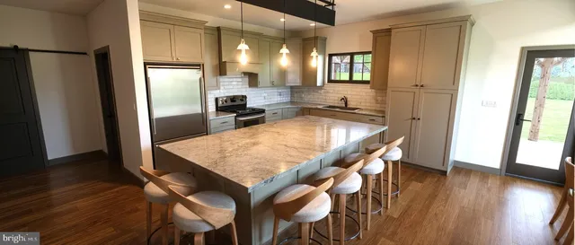 a kitchen with stainless steel appliances granite countertop wooden floor and refrigerator