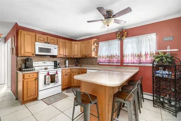 a kitchen with stainless steel appliances granite countertop a stove a sink a microwave a refrigerator and chairs