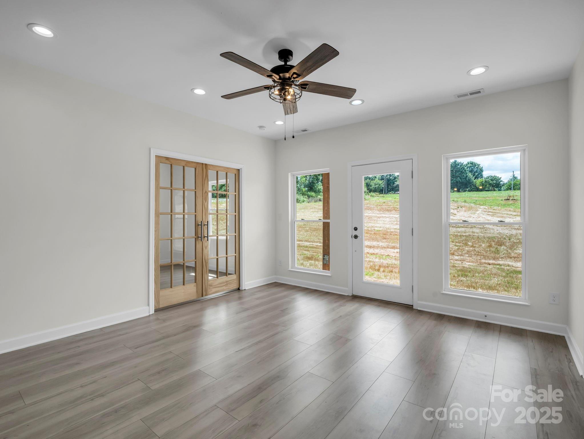 174 Charlie Randall Road Lawndale, NC 28090 - Photo 28 of 41 an empty room with wooden floor chandelier fan and windows