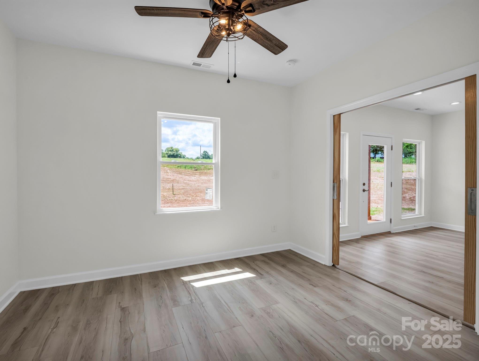 174 Charlie Randall Road Lawndale, NC 28090 - Photo 32 of 41 an empty room with wooden floor chandelier fan and windows