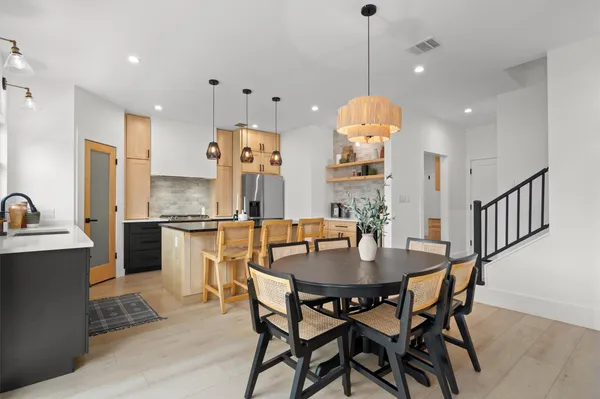a kitchen with stainless steel appliances kitchen island granite countertop a table chairs and a refrigerator