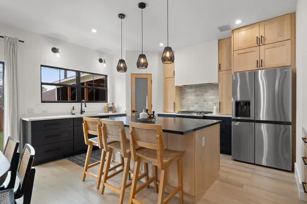 a kitchen with stainless steel appliances a refrigerator a stove a sink and chairs