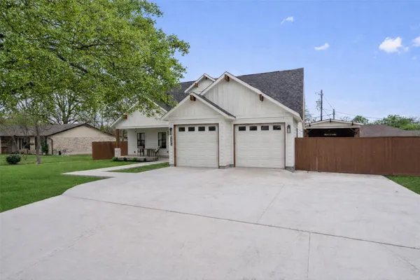 a view of a house with a yard and large tree