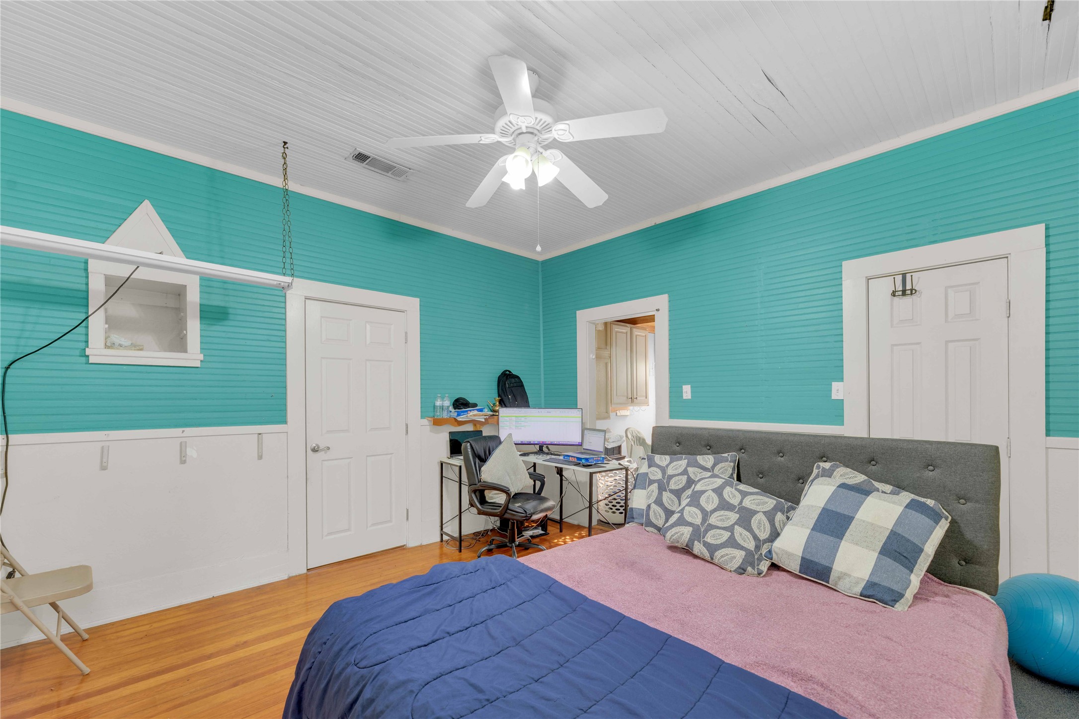 20235 Engelmann Lane Manor, TX 78653 - Photo 24 of 34 Bedroom featuring wood finished floors, a closet, ceiling fan, and wainscoting