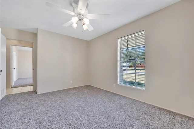 an empty room with windows and fan