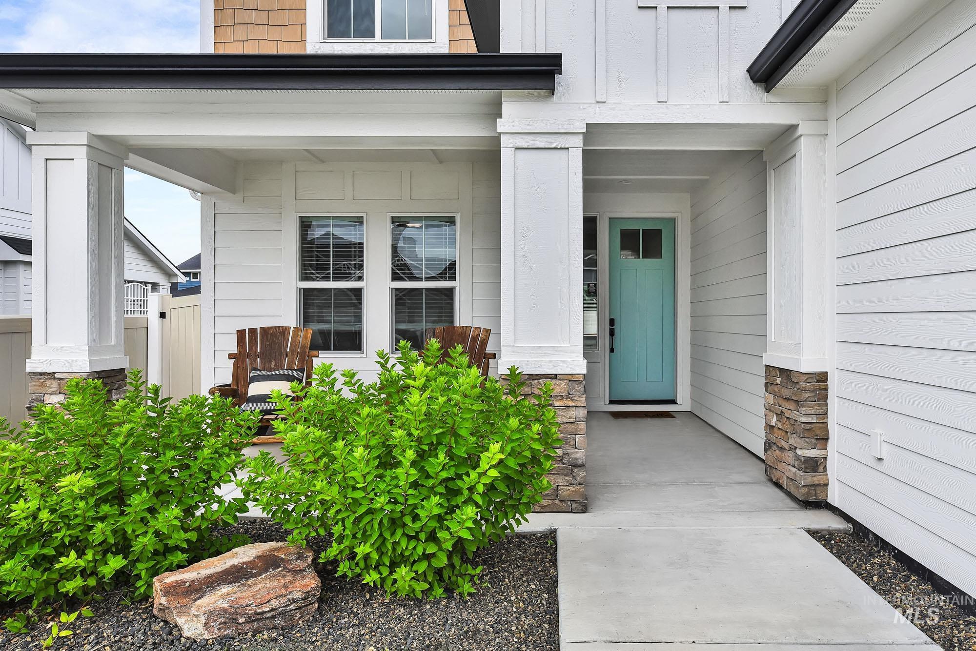 5676 East Zaffre Ridge Street Boise, ID 83716 - Photo 2 of 50 Inviting covered front porch with stone-wrapped columns, a vibrant turquoise entry door with divided lites, and white horizontal siding