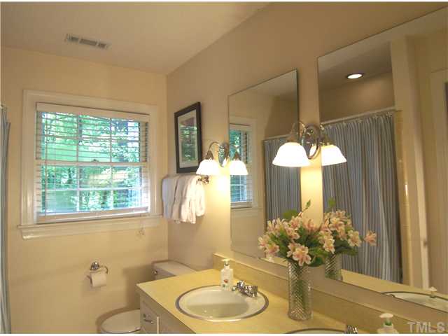 4920 Brookhurst Place Raleigh, NC 27609 - Photo 19 of 24 a bathroom with a granite countertop sink a large mirror and a shower