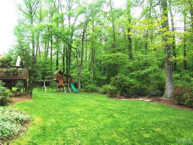 4920 Brookhurst Place Raleigh, NC 27609 - Photo 21 of 24 a view of a backyard with a slide trees and wooden fence