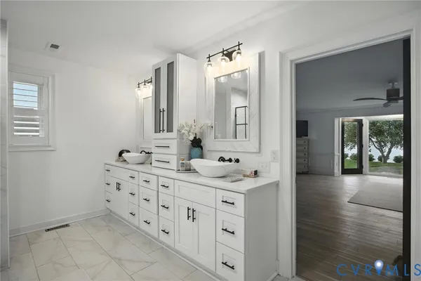 a spacious bathroom with a double vanity sink a mirror and next to a window