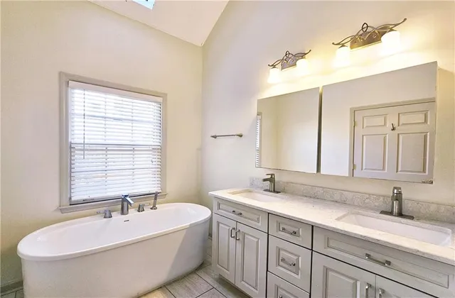 a spacious bathroom with a double vanity sink mirror and a bathtub