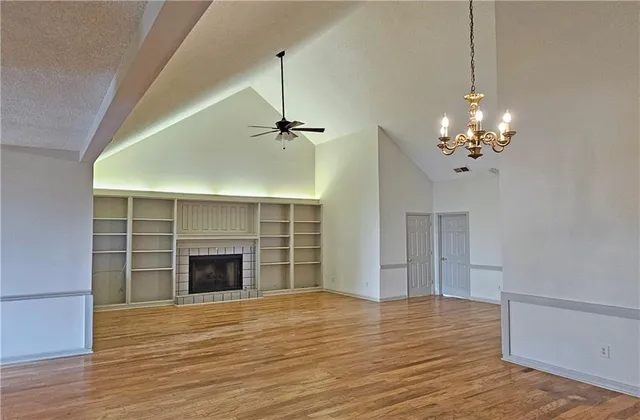 a view of an empty room with wooden floor fireplace and a window