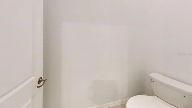 a white toilet sitting next to a white wall