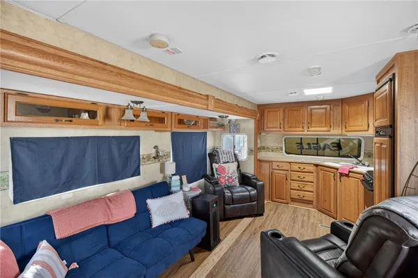 a living room with stainless steel appliances furniture a rug and a kitchen view