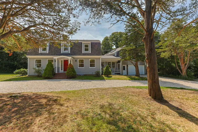 a front view of a house with a yard and trees