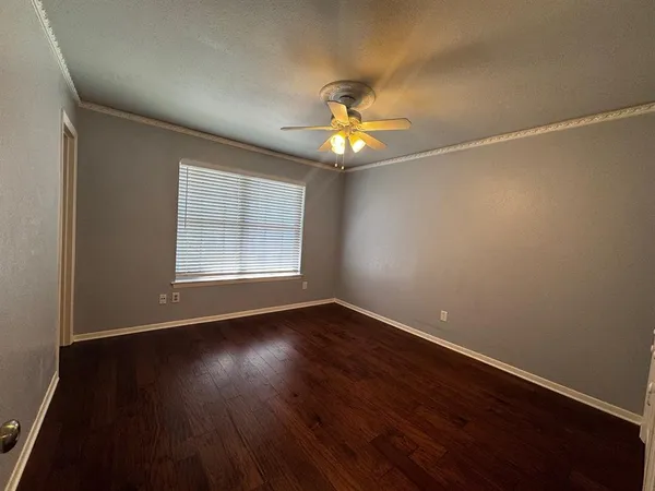 an empty room with wooden floor chandelier fan and windows