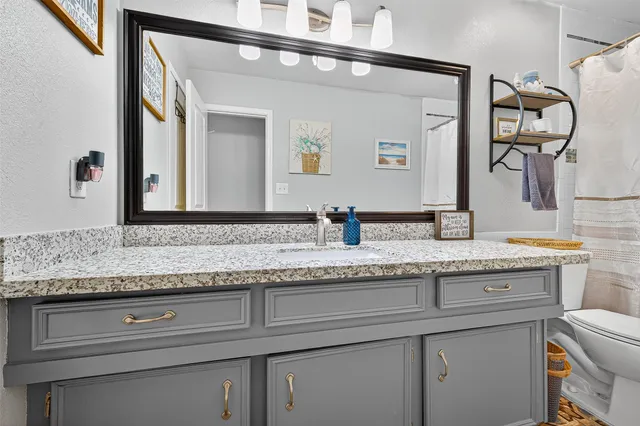 a bathroom with a granite countertop sink and a mirror