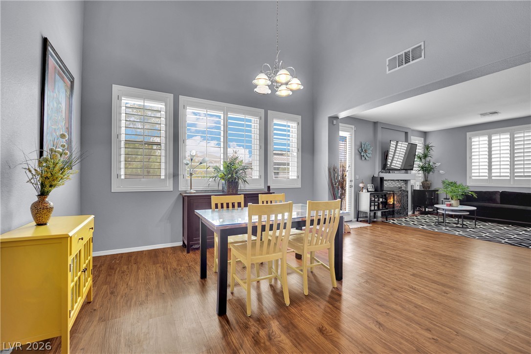 1724 Millstream Way Henderson, NV 89074 - Photo 58 of 60 An open floorplan offers seamless flow between the dining and living spaces, illuminated by natural light and overhead chandelier.