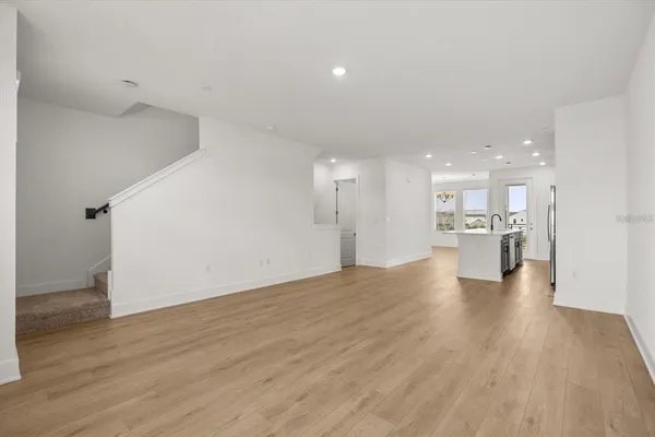 a view of a big room with wooden floor and a kitchen