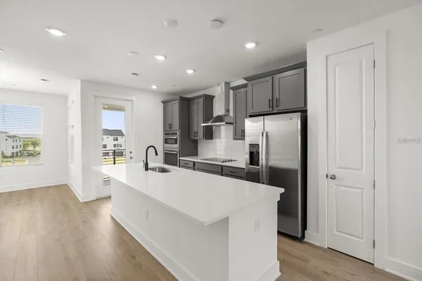 a large kitchen with a center island wooden floor stainless steel appliances and windows