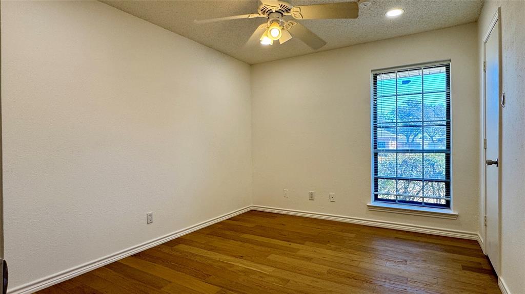 3915 Spring Hollow Drive Carrollton, TX 75007 - Photo 25 of 28 an empty room with wooden floor cabinet and windows