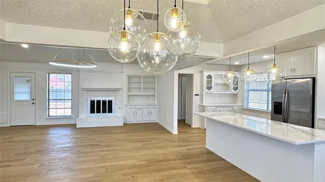 a large kitchen with stainless steel appliances granite countertop a refrigerator a stove and white cabinets with wooden floor