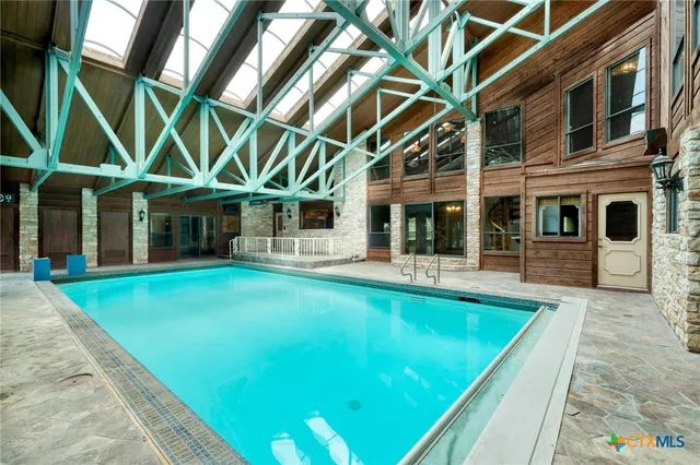 a view of pool with lawn chairs and large trees with plants