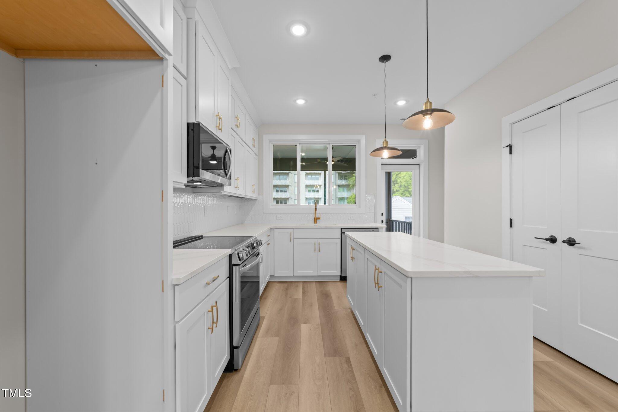 710 West North Street, Unit 101 Raleigh, NC 27603 - Photo 11 of 28 a kitchen with kitchen island a counter top space a sink stainless steel appliances and cabinets