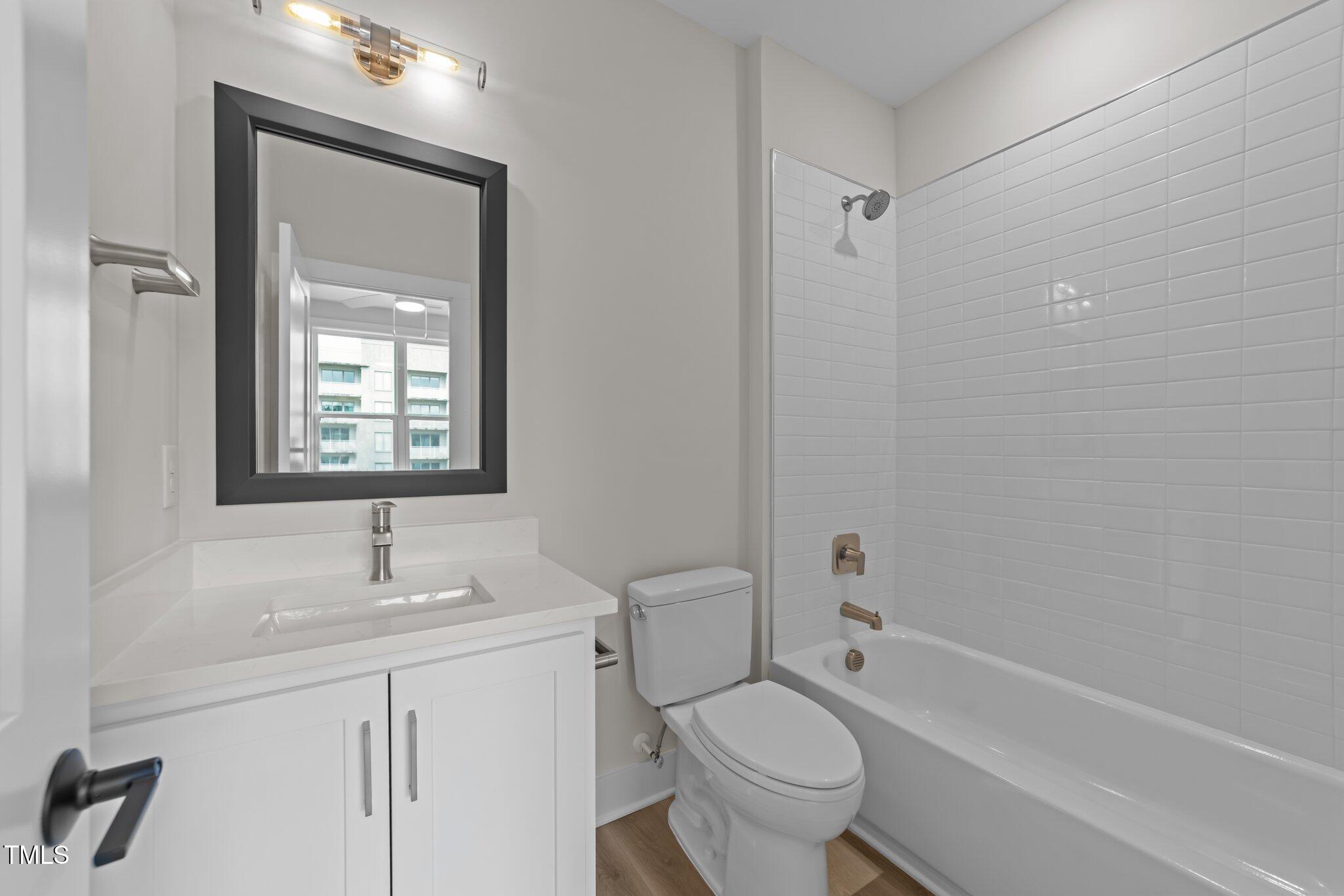 710 West North Street, Unit 101 Raleigh, NC 27603 - Photo 23 of 28 a bathroom with a toilet a sink a mirror a bathtub and shower