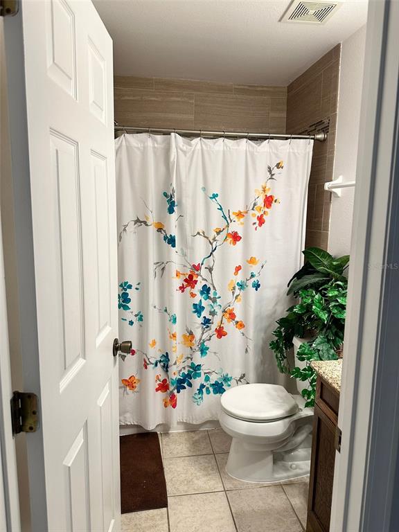 242 Durango Loop Street Davenport, FL 33897 - Photo 11 of 30 a white toilet sitting next to a white curtain and a shower curtain