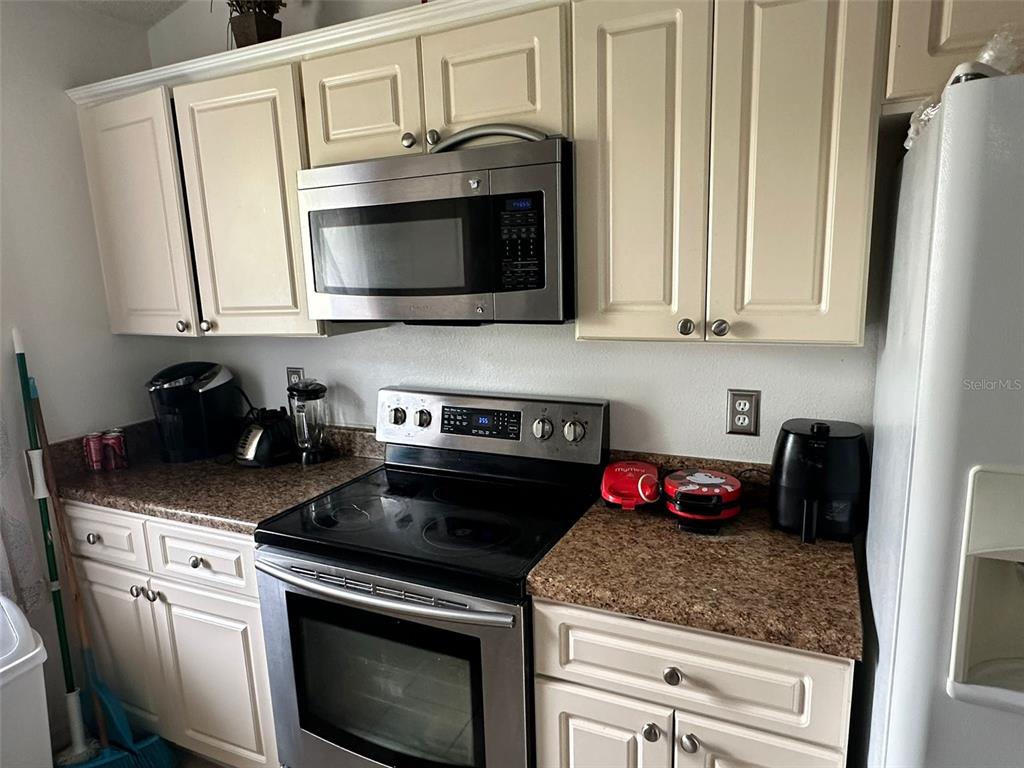 242 Durango Loop Street Davenport, FL 33897 - Photo 5 of 30 a kitchen with stainless steel appliances granite countertop a sink stove and microwave