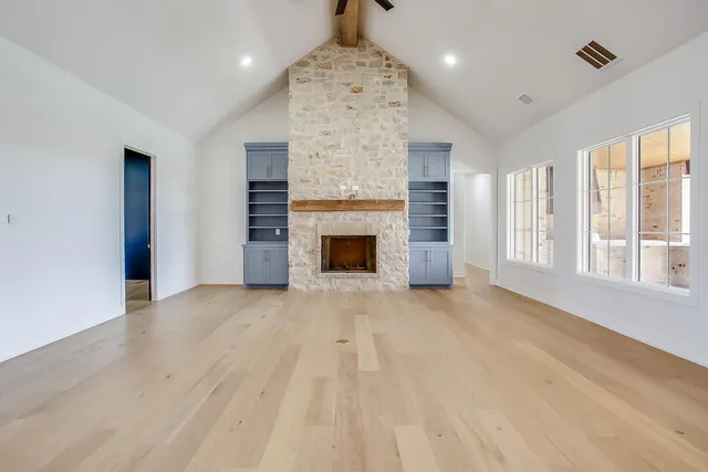 an empty room with windows and fireplace