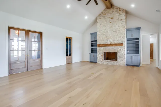 an empty room with windows and fireplace