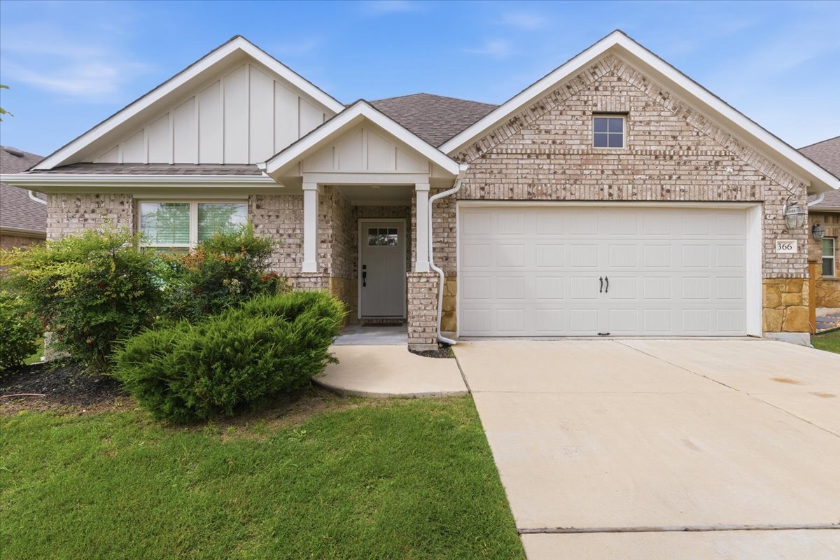 Brick and stone exterior with two-car garage, covered entry, and well-maintained landscaping