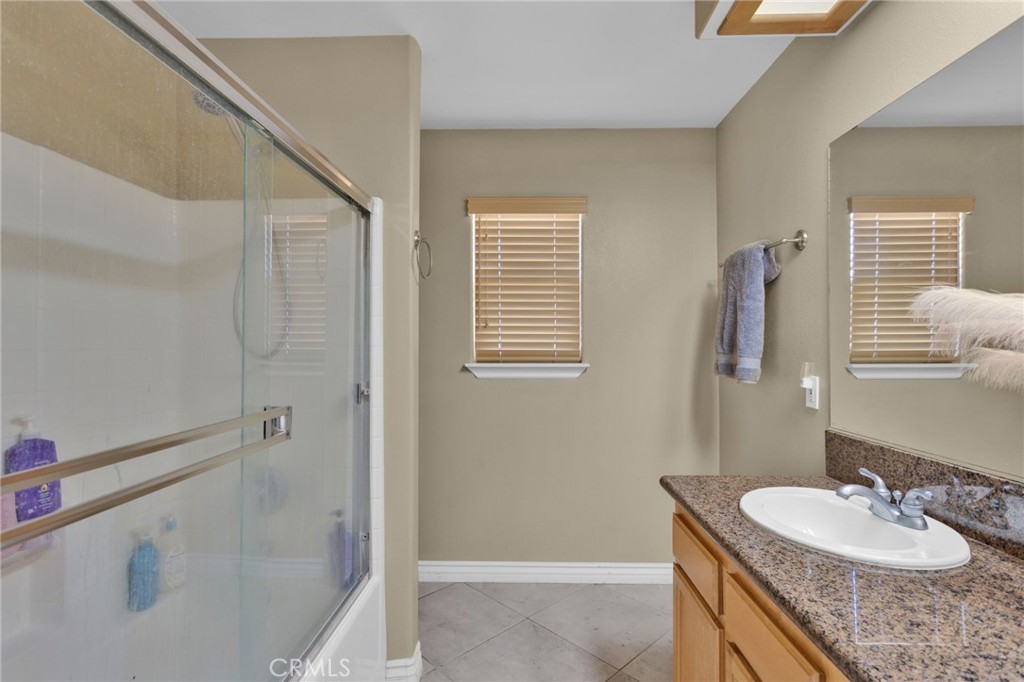 13597 Kiowa Road Apple Valley, CA 92308 - Photo 32 of 44 a bathroom with a granite countertop sink a mirror and a shower