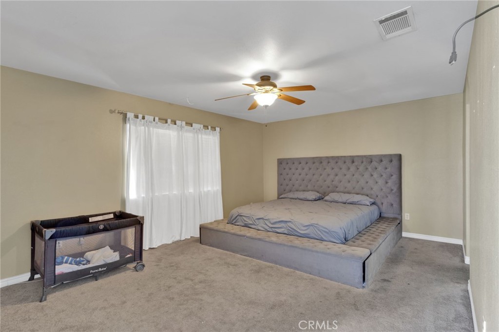 13597 Kiowa Road Apple Valley, CA 92308 - Photo 35 of 44 a spacious bedroom with a bed and a chandelier