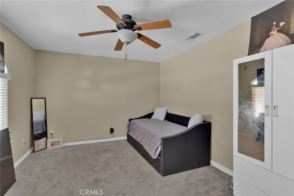 13597 Kiowa Road Apple Valley, CA 92308 - Photo 40 of 44 a bedroom with a bed and a ceiling fan