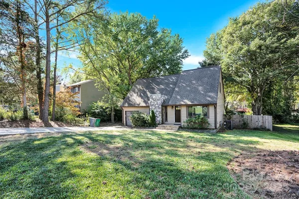 a brick house with a big yard and large trees
