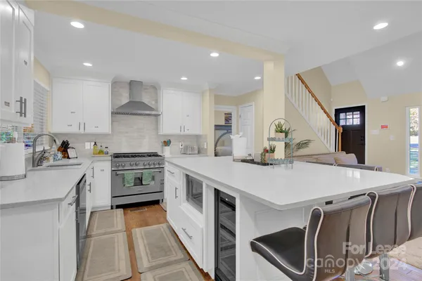 a kitchen with stainless steel appliances a stove a sink a stove a refrigerator cabinets and a dining table