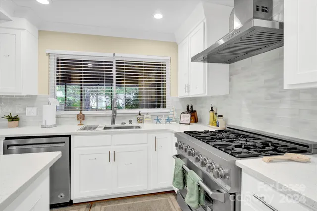 a kitchen with a stove a sink a window and cabinets