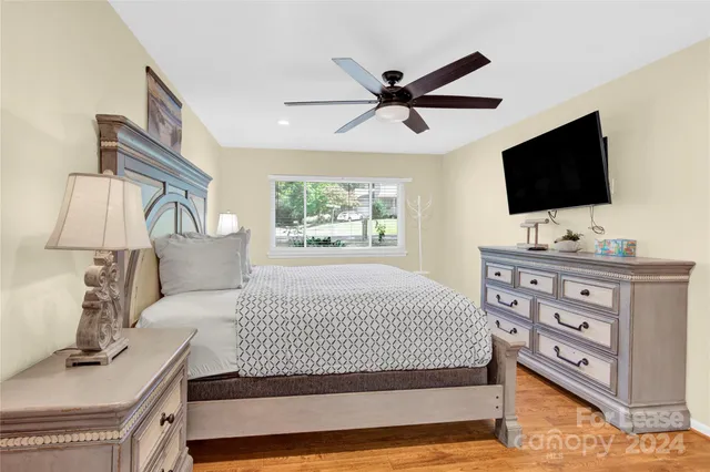 a bedroom with a large bed and a flat tv screen on a dresser