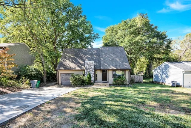 a brick house with a big yard plants and large trees