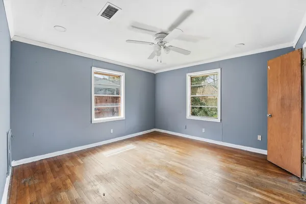 a view of empty room with wooden floor and fan