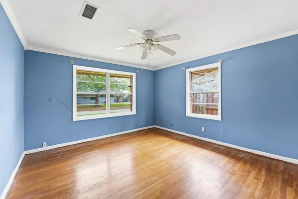 a view of an empty room with a window and wooden floor