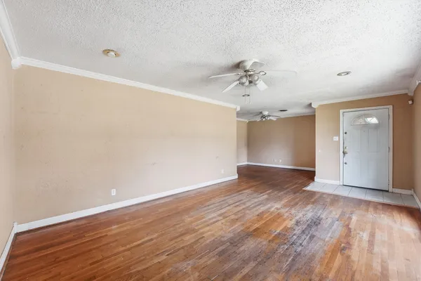 an empty room with wooden floor and ceiling fan