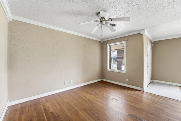 a view of an empty room with wooden floor and a window