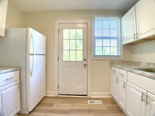 a view of a kitchen with white cabinets and refrigerator
