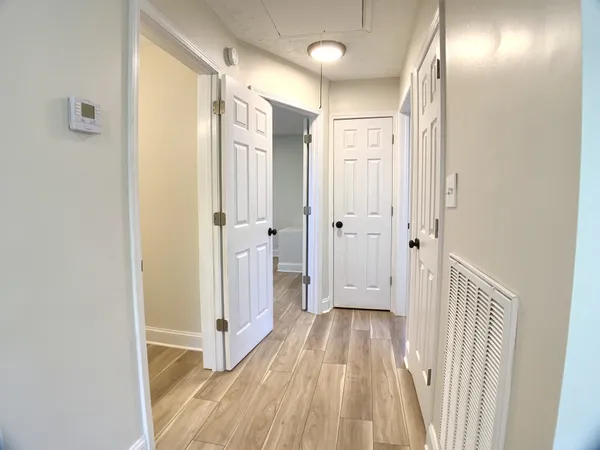 a view of a hallway with wooden floor and a bathroom