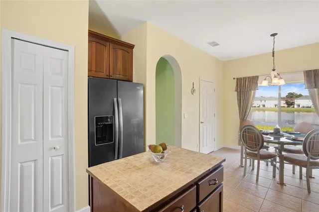 a kitchen with stainless steel appliances kitchen island granite countertop a refrigerator a stove a dining table and chairs