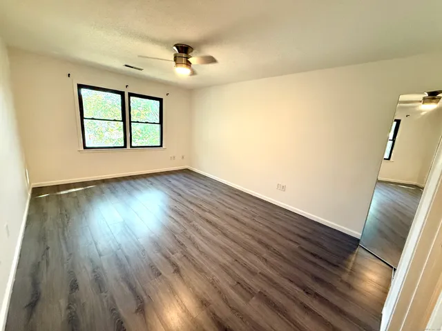 a view of an empty room with wooden floor and a window